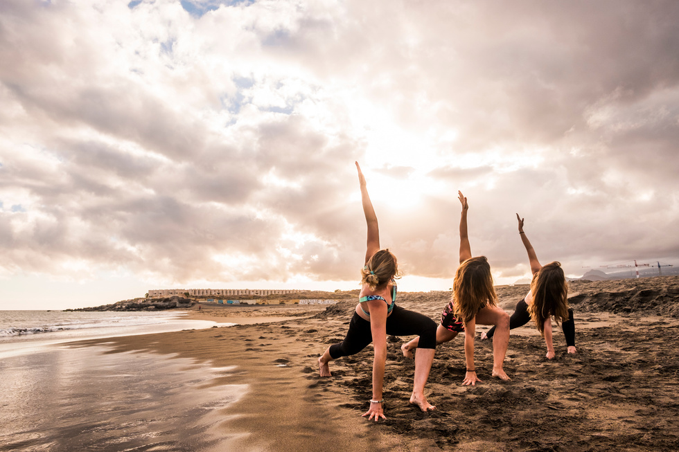 Group of Young Women Practicing Yoga at the Beach 